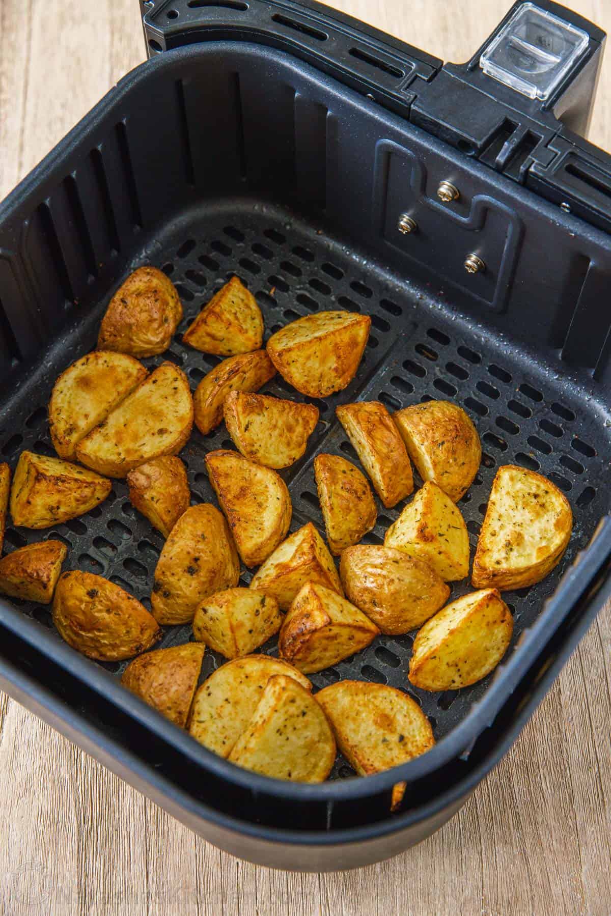 These easy, 20-minute air fryer roasted potatoes are ready in half the time as oven-roasted potatoes and they turn out just as crispy! Overhead view of roasted potatoes inside the air fryer basket.