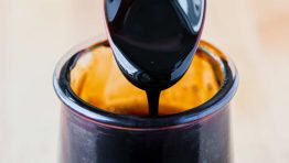 Balsamic glaze pouring off a spoon into jar