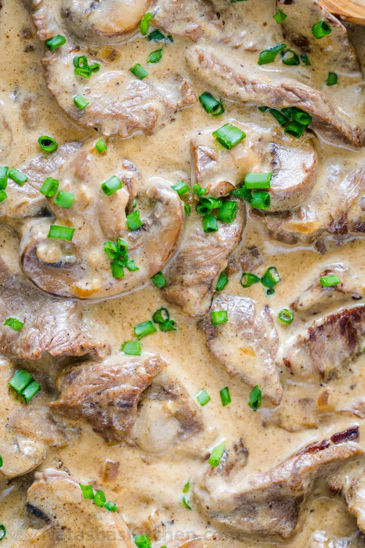 Classic Beef Stroganoff with tender strips of beef and mushrooms in an creamy Stroganoff sauce, served over noodles. An easy, one-pan, 30-minute recipe! #beefstroganoff #beefstroganoffrecipe #stroganoff #beef #beefrecipes #dinner #onepandinner #natashaskitchen Beef and mushrooms in creamy stroganoff sauce garnished with green onion