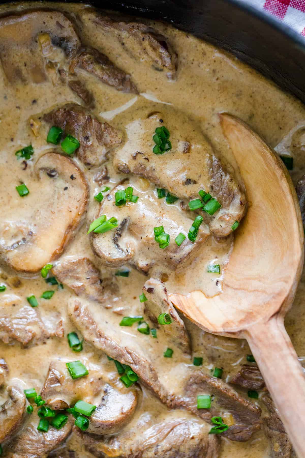 Classic Beef Stroganoff with tender strips of beef and mushrooms in an creamy Stroganoff sauce, served over noodles. An easy, one-pan, 30-minute recipe! #beefstroganoff #beefstroganoffrecipe #stroganoff #beef #beefrecipes #dinner #onepandinner #natashaskitchen Beef stroganoff recipe up close in pan