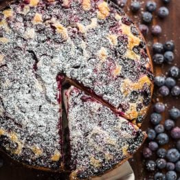 Lemon Blueberry Cake dusted with powdered sugar and slice cut out