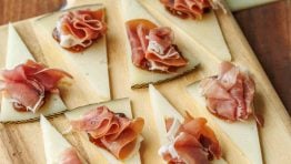 Manchego Cheese Bites on a cutting board with fig spread in the background