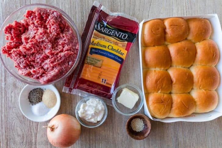 Ingredients for mini cheeseburgers with Hawaiian dinner rolls, ground beef, cheese, mayo, onion, seasonings, butter and sesame seeds