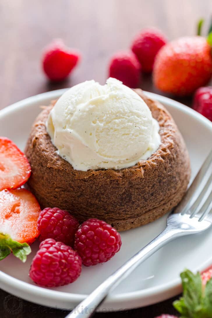 Chocolate lava cake topped with vanilla ice cream on a plate with berries