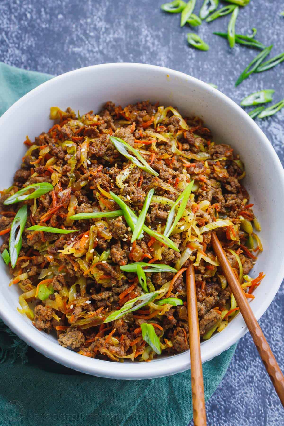 Enjoy the BEST recipe for Egg Roll in a Bowl ready in just 20 minutes. Egg Roll Bowls are made with ground beef, cabbage, veggies, and sauce. Deconstructed egg roll in a bowl with two chopsticks.