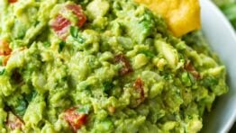 Guacamole served in a white bowl with a tortilla chip