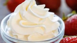 homemade whipped dream piped into a small bowl with strawberries for dipping