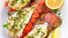 Lobster tails on a serving platter served with lemon wedges