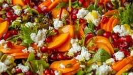 pouring dressing from a glass jar onto the persimmon salad