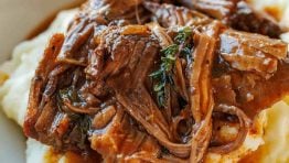 classic pot roast recipe served over mashed potatoes in a white bowl