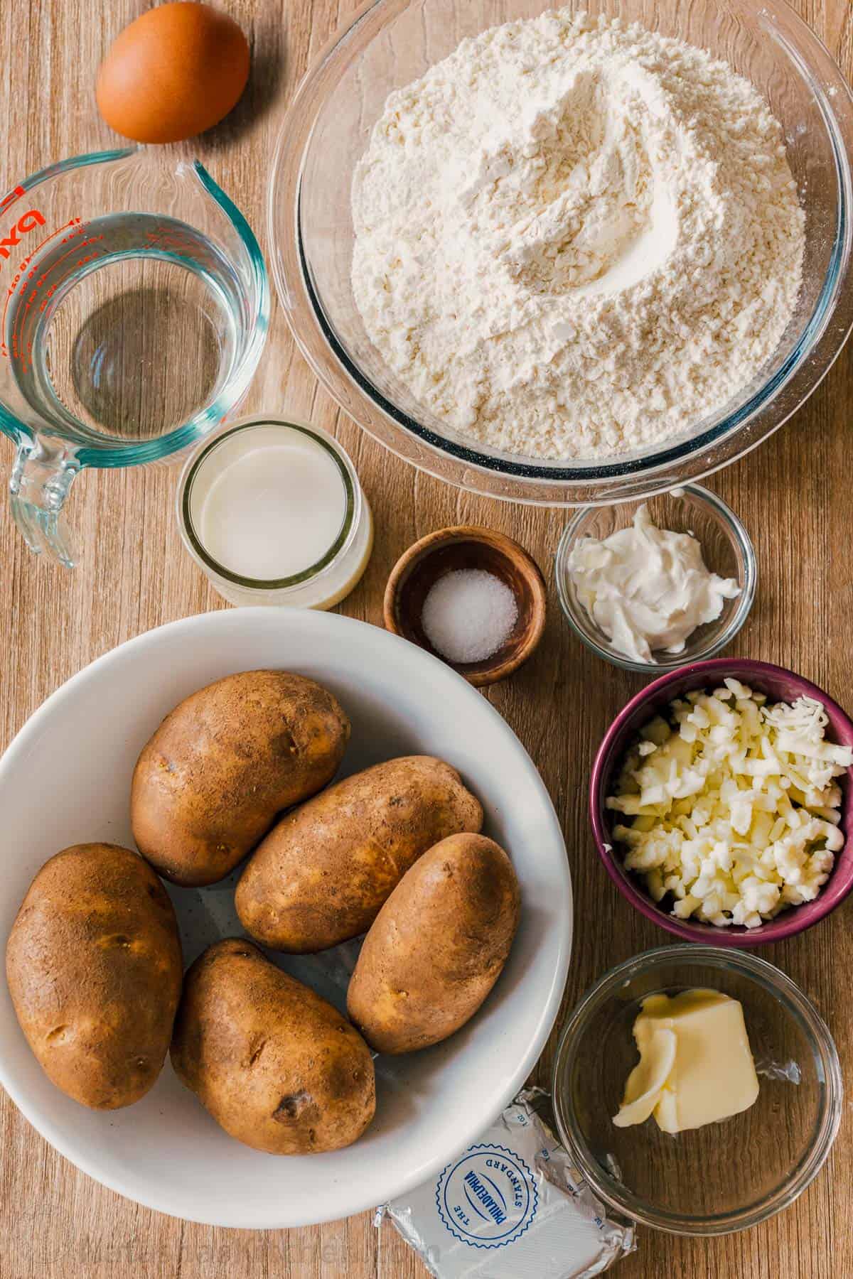 Pierogi filled with cheesy potatoes and served with crisp bacon, melted butter and sour cream. Homemade Pierogi is the ultimate comfort food! Ingredients for making potato and cheese dumplings