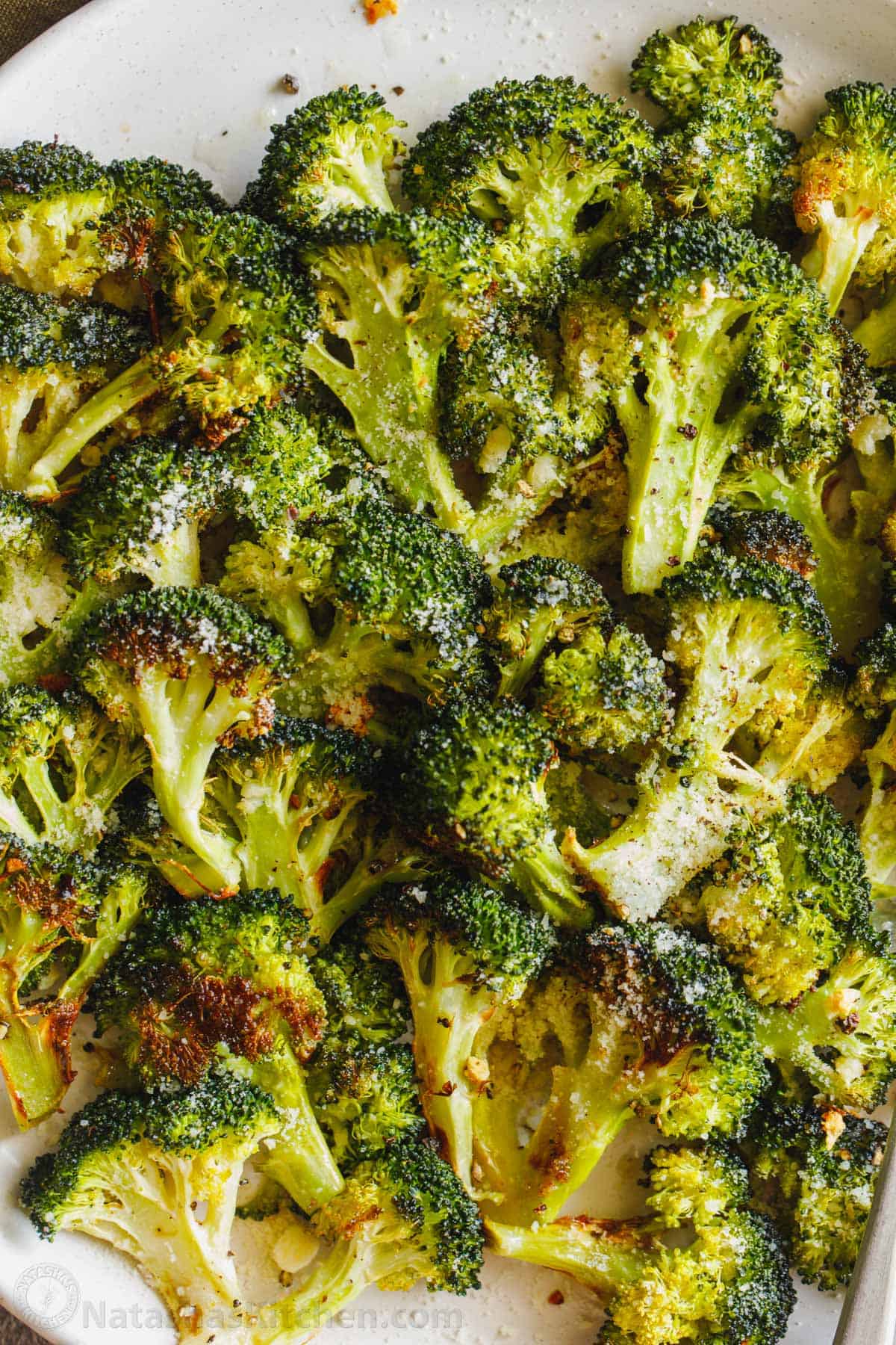 The Best Roasted Broccoli Recipe with crisp golden edges. Tossed with olive oil and perfectly seasoned for an easy, excellent broccoli side. Roasted Broccoli on a plate garnished with parmesan cheese