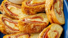 Stromboli sliced into pinwheels on a plate with marinara dipping sauce in a ramekin